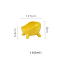 Green ceramic cat food bowl with four legs and rounded arc design on wooden floor