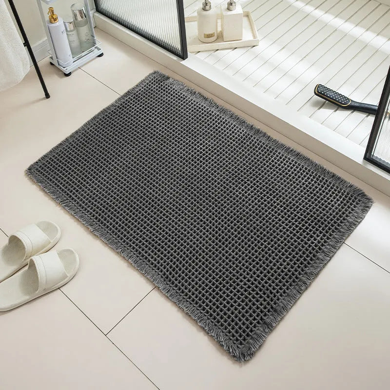 Modern checkered pattern absorbent non-slip bathroom floor mat in a neutral colour on tiled floor.