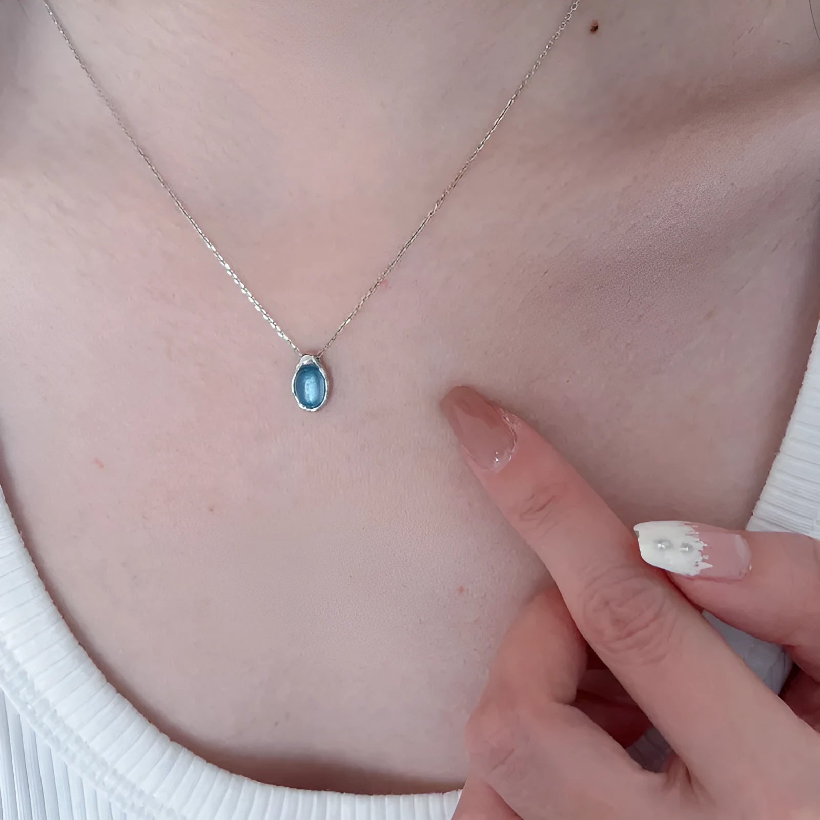 Navy blue geometric water drop pendant necklace on model showing adjustable cross chain design