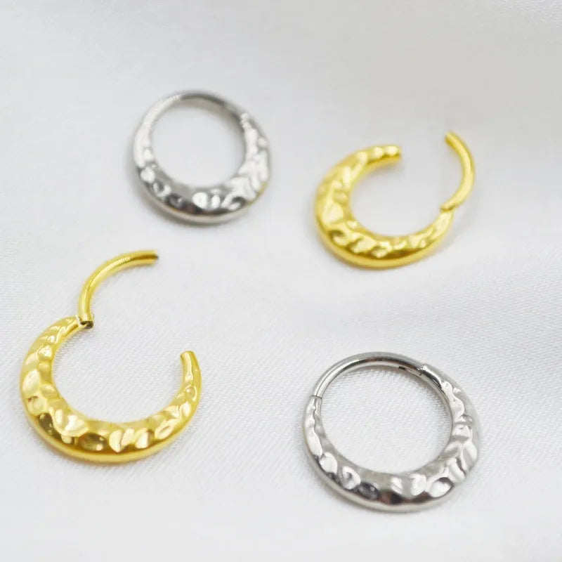 Titanium alloy concave-convex nose ring in gold and silver finishes showing surface texture detail