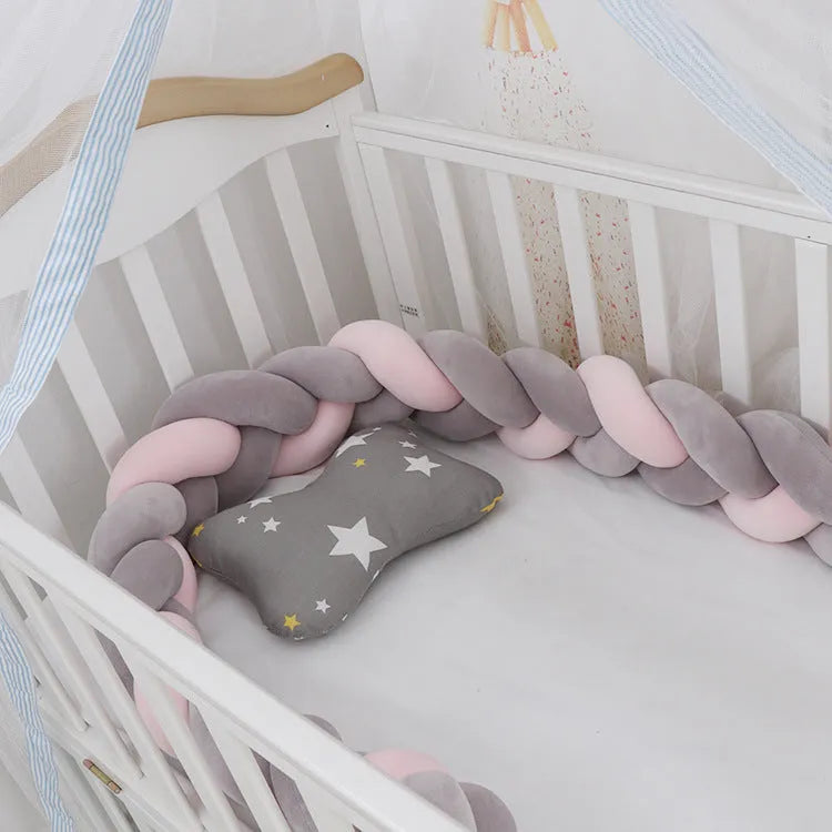 Bendable braid-knot baby crib bumper in spandex velvet, shown in a light grey colour wrapped around a cot.