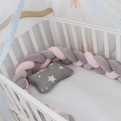 Bendable braid-knot baby crib bumper in spandex velvet, shown in a light grey colour wrapped around a cot.