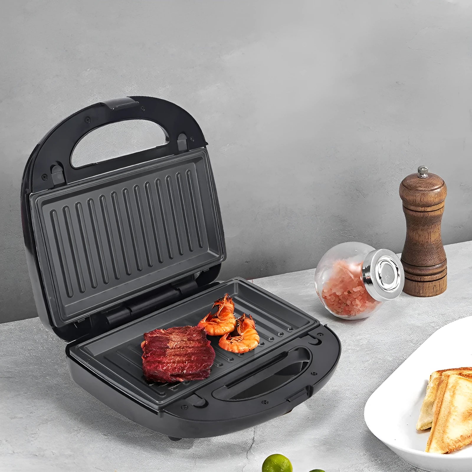 Black double-sided electric sandwich pan with brushed stainless steel lid and non-stick plates.