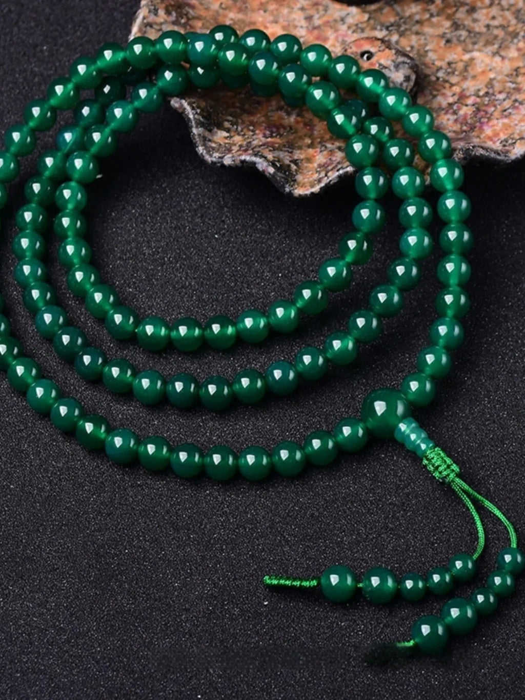 Natural green agate 108-bead bracelet with pendant in Thangka style on a wrist.