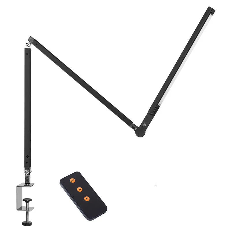 Folding aluminium desk lamp with a metal clip, shown in dazzling black, attached to a desk edge.