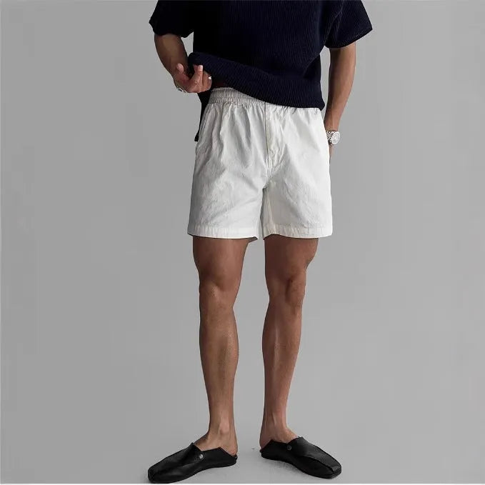 Men's loose-fit cotton sports shorts in black, shown on a hanger.