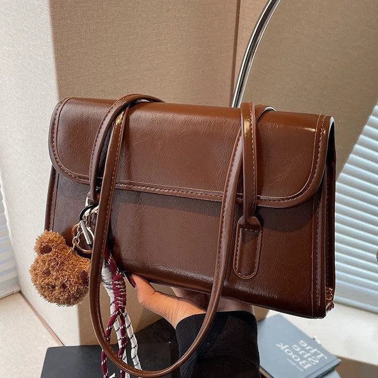 Women's brown PU leather shoulder bag with square shape, double straps, and decorative pendant attachment