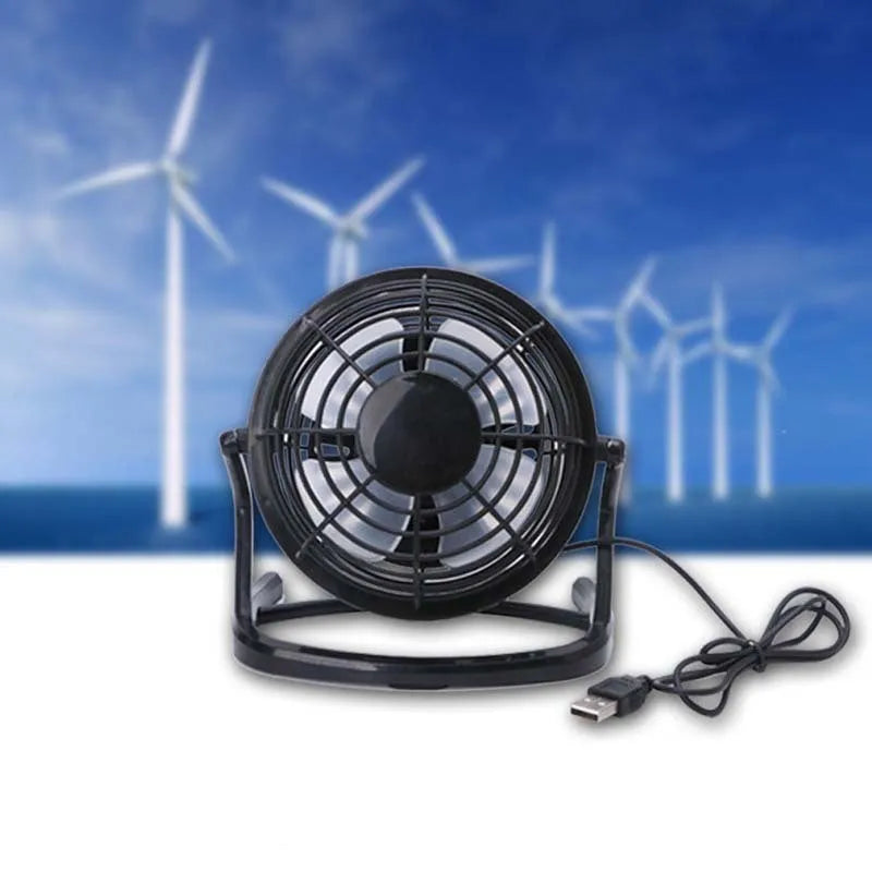 Black mini USB desk fan with adjustable head on a wooden desk next to a laptop.