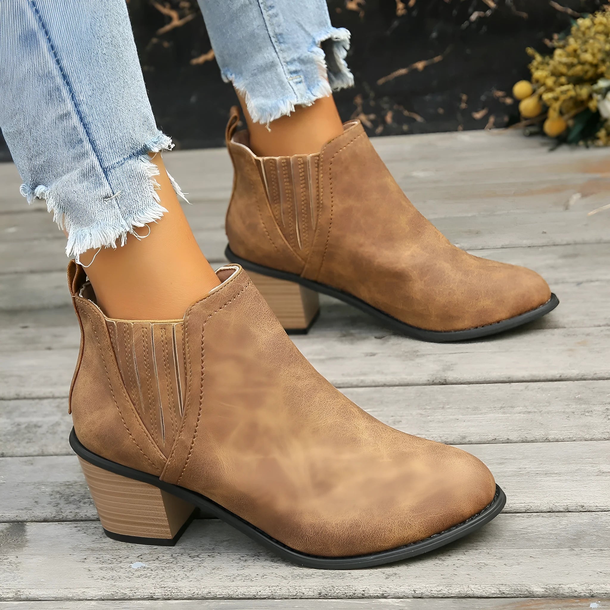 Black pointed toe ankle boots with a thick square low heel on a woman's foot.