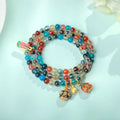Close-up of a women's snake chain bracelet with colourful agate hearts and detailed copper coins.