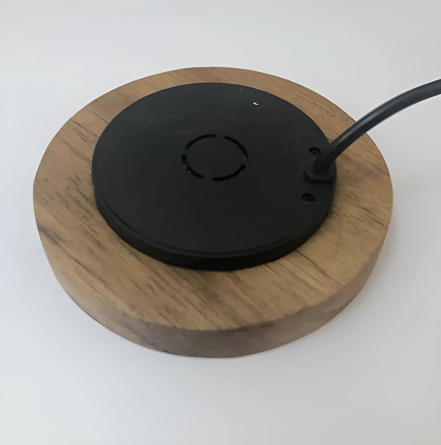 Round hidden wireless charger for embedding in desks, compatible with iPhone and Samsung phones.