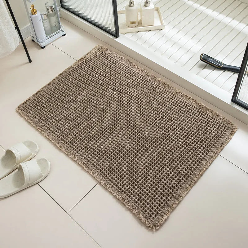 Modern checkered pattern absorbent non-slip bathroom floor mat in a neutral colour on tiled floor.