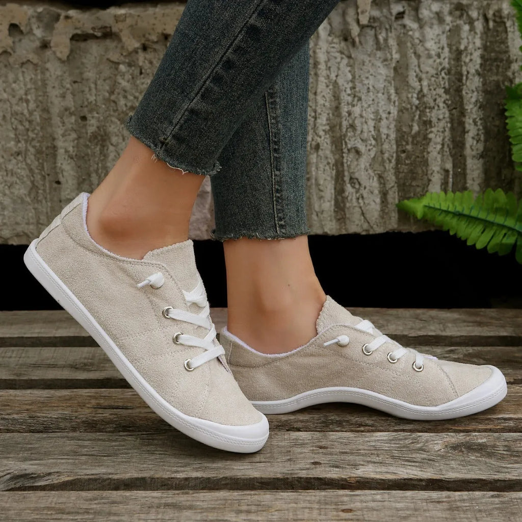 Women's creamy white low-top fabric sneakers with rubber soles on various surfaces