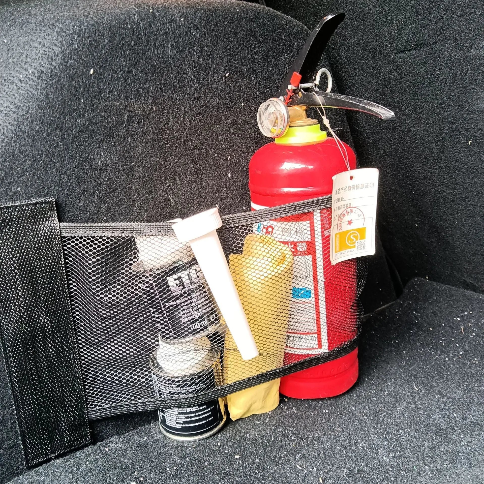 Elastic car boot storage net organiser holding various loose items securely in place