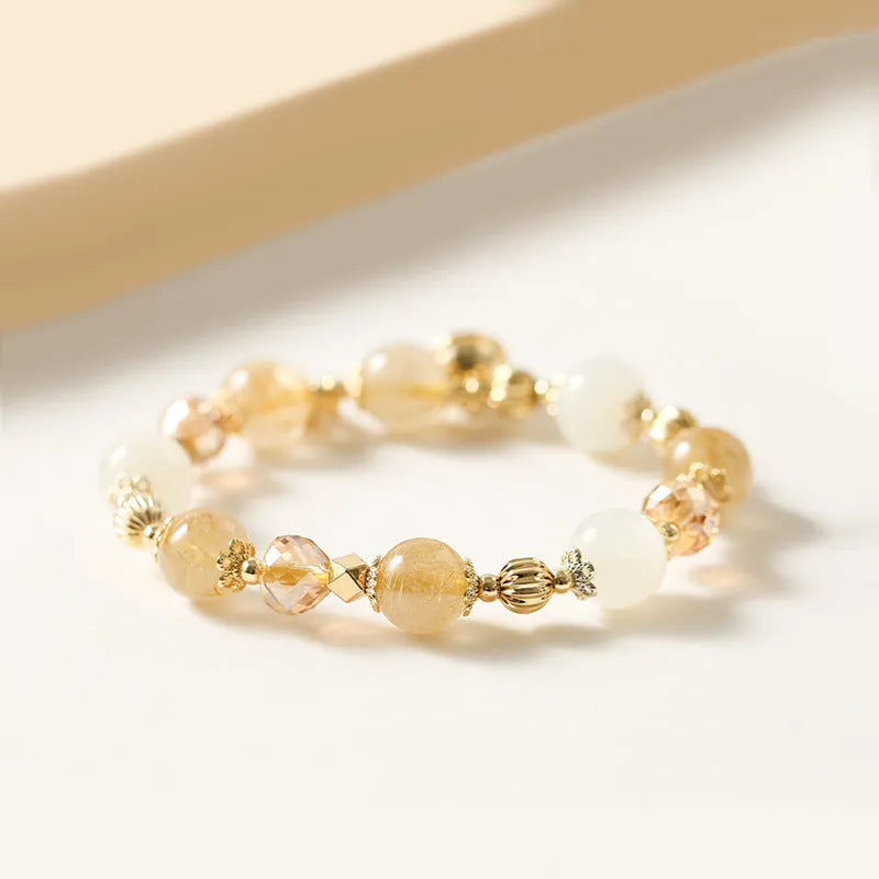 Gold rutilated quartz bracelet with bell charm on wrist
