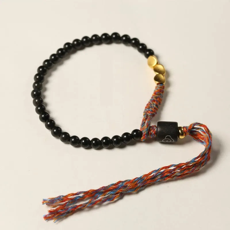 Hand-woven obsidian carrying strap bracelet showing textured weave and adjustable length