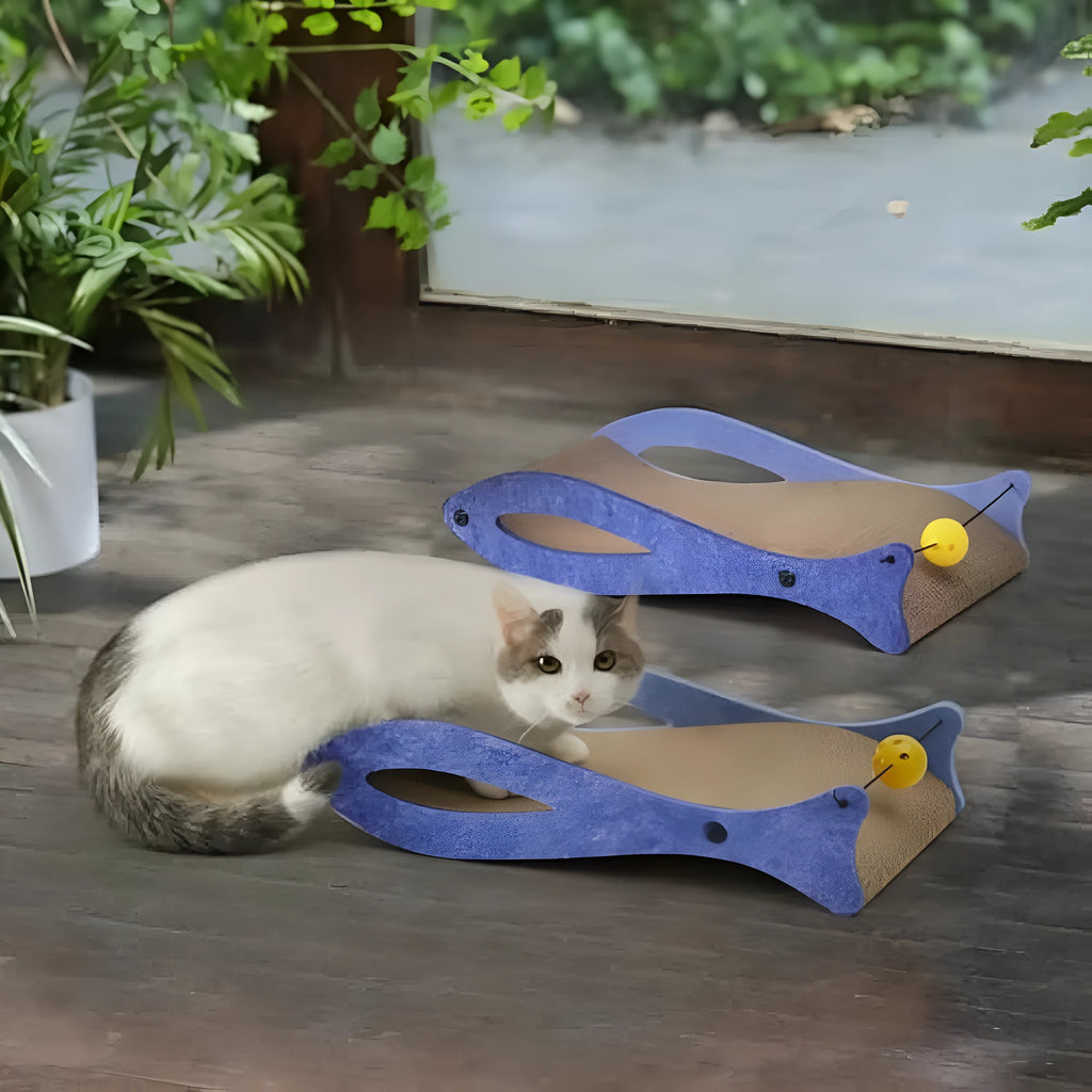 Blue fish-shaped cat scratcher pad with corrugated cardboard surface, ball toys, and wavy lounge area.
