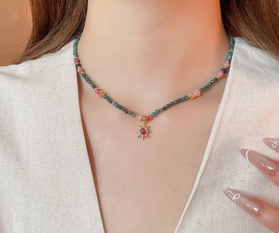 French royal style sun necklace with freshwater pearls and a blue stone geometry pendant on a gold chain.