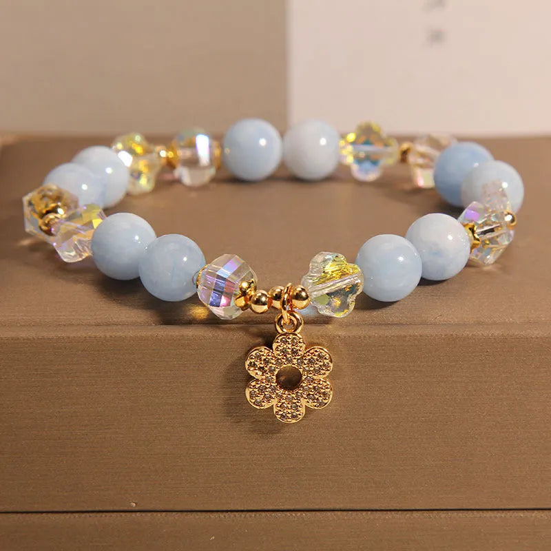 Women's aquamarine crystal four-leaf clover bracelet with pearl accents on a silver chain.