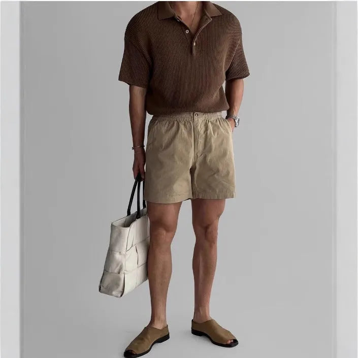 Men's loose-fit cotton sports shorts in black, shown on a hanger.