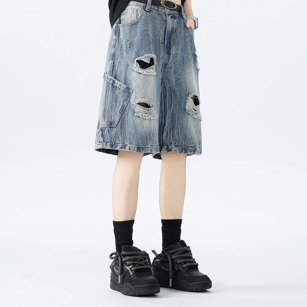 Loose washed blue denim shorts with a ripped knee detail on a mannequin, showing the retro fit.