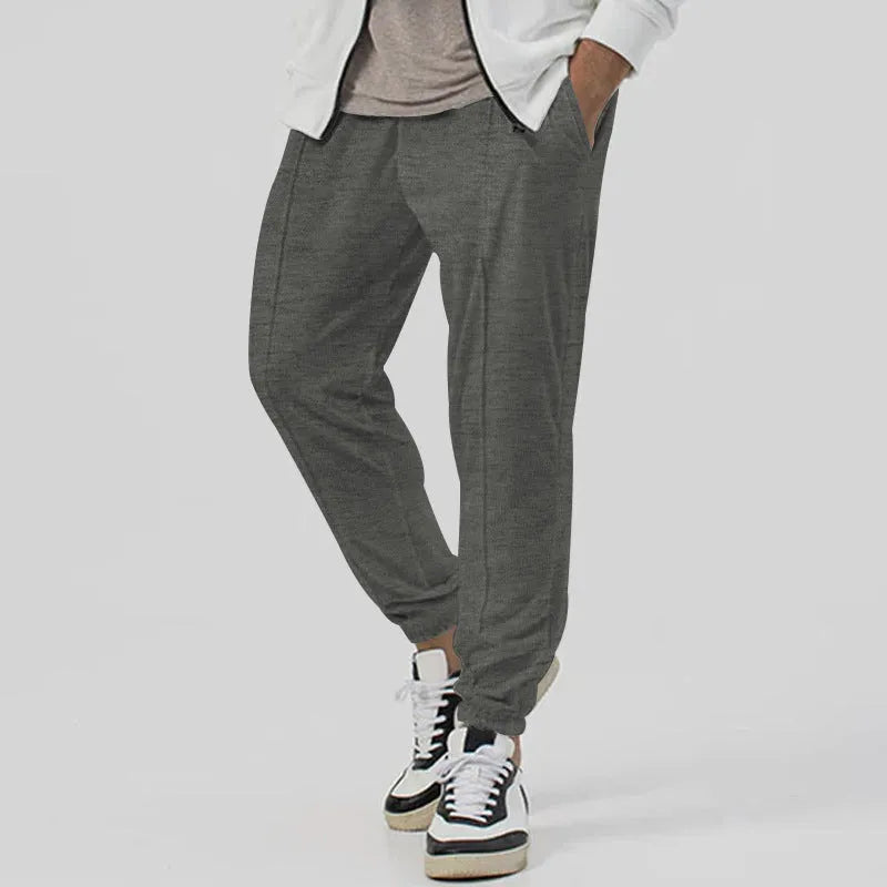 Men's grey loose-fit tapered track sweatpants with a straight leg on a neutral background.