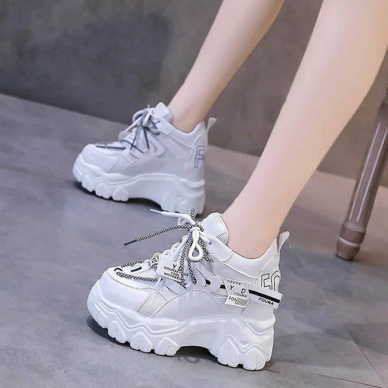 White and black women's mesh platform sports shoes with cross-strap and rubber sole.