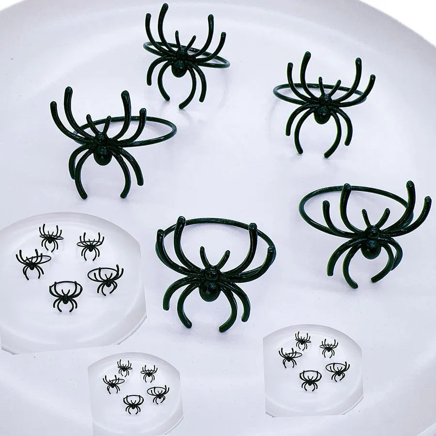 Set of six black alloy napkin rings with spider design for Halloween table decoration.