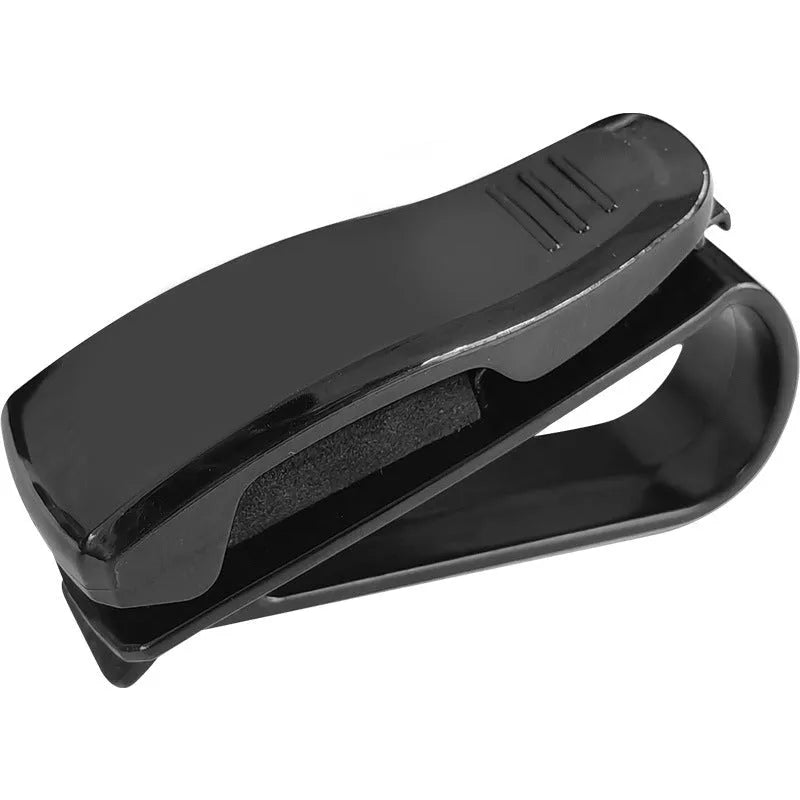 Black plastic car sunshade clip holding sunglasses and parking ticket