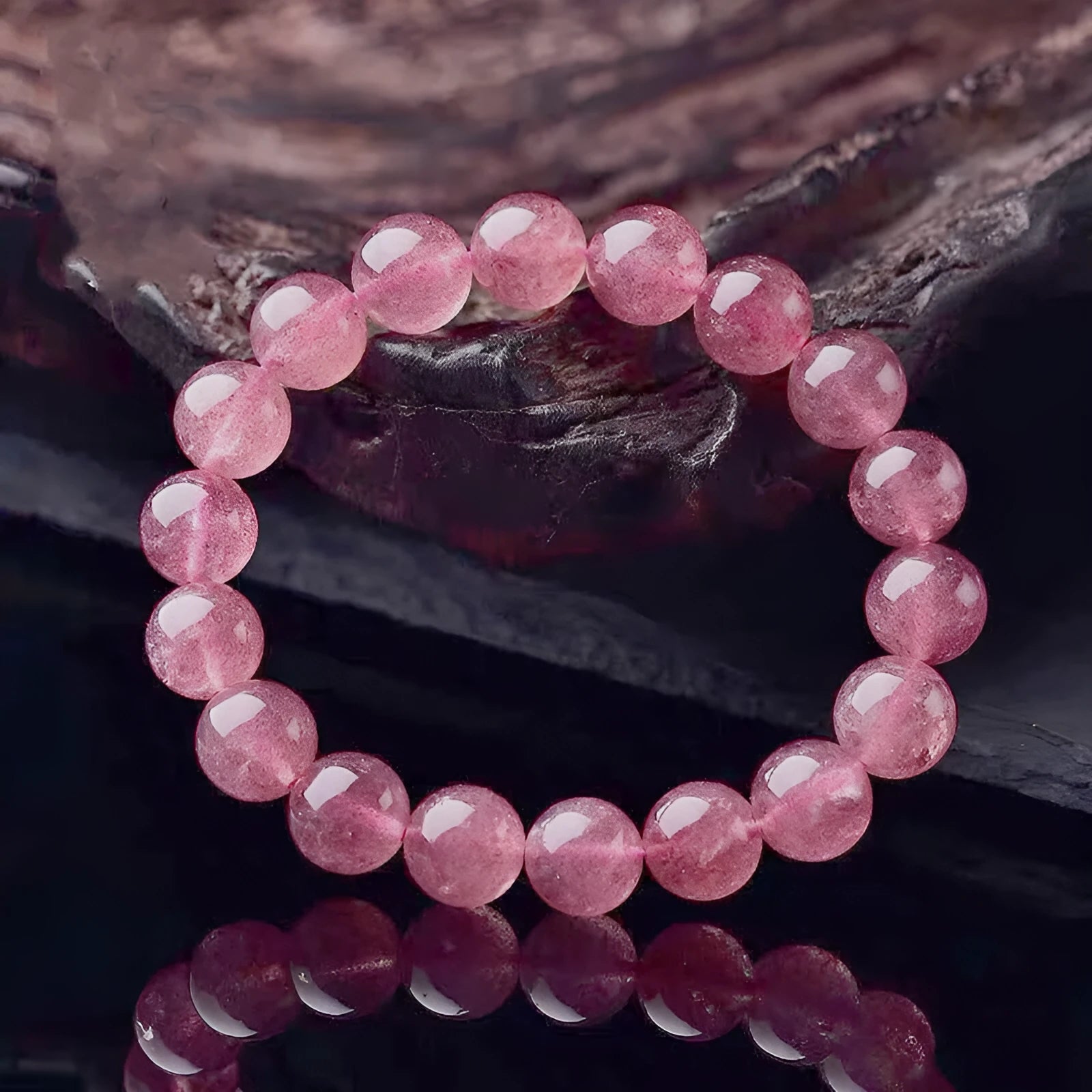 Women's strawberry quartz crystal bracelet with polished beads on a wrist.