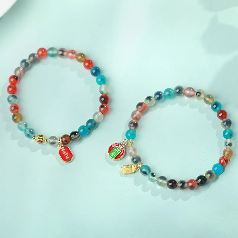 Close-up of a women's snake chain bracelet with colourful agate hearts and detailed copper coins.