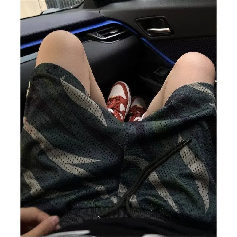 Men's straight-cut camouflage mesh shorts in cotton blend fabric on a hanger.