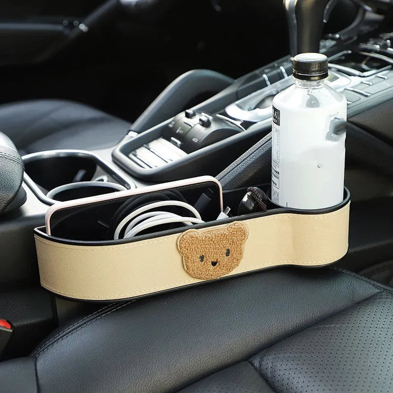 Car seat gap storage organiser with cartoon bear design hanging between vehicle seats