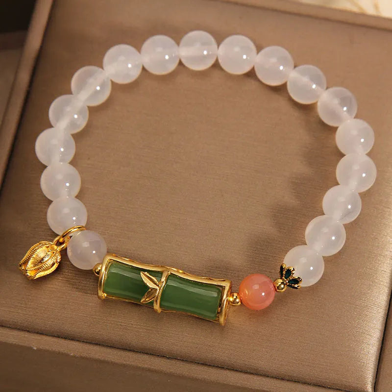 Close-up of a white agate jasper beaded bracelet with a jade bead in a Chinese bamboo style.