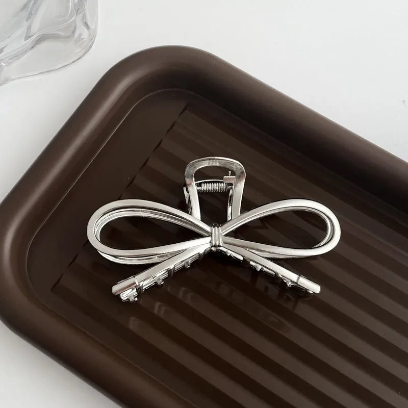 Silver metal hair claw clip assortment showing bows, waves, pearl designs, and geometric shapes from 4cm to 13.5cm