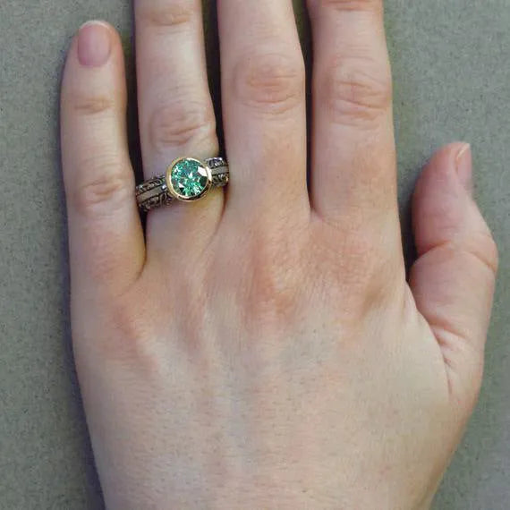 Gold-plated women's ring with flower design featuring green gemstone accents and colour separation details
