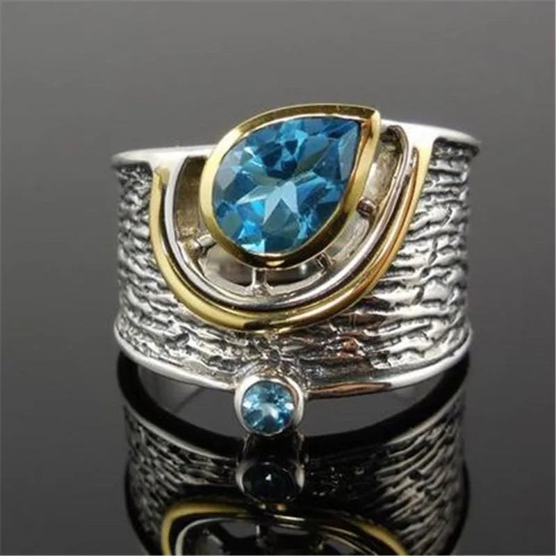 Blue zircon drop shape ring with Chinese style inlaid design on alloy band.