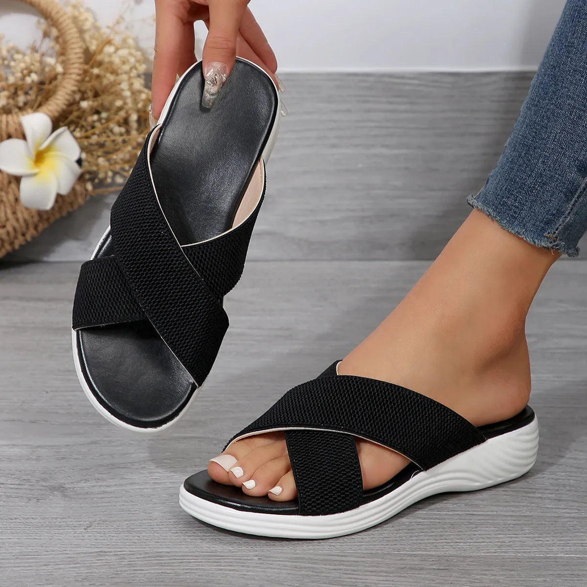 Black wedge platform slippers with a cross strap and open peep-toe design on a white background.