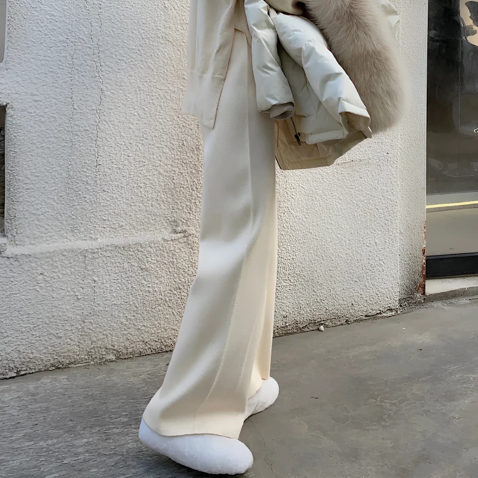 Women's cream white high waist wide-leg knitted trousers with a long mopping hem and elastic waistband.