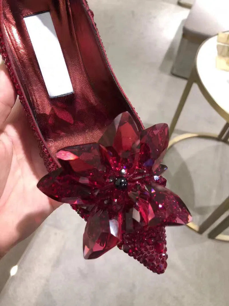 Gold women's pointed toe stiletto heels with rhinestone and bow decoration on a sequin cloth upper.