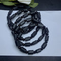 Black tourmaline rough stone bracelet with unpolished beads on a wrist.