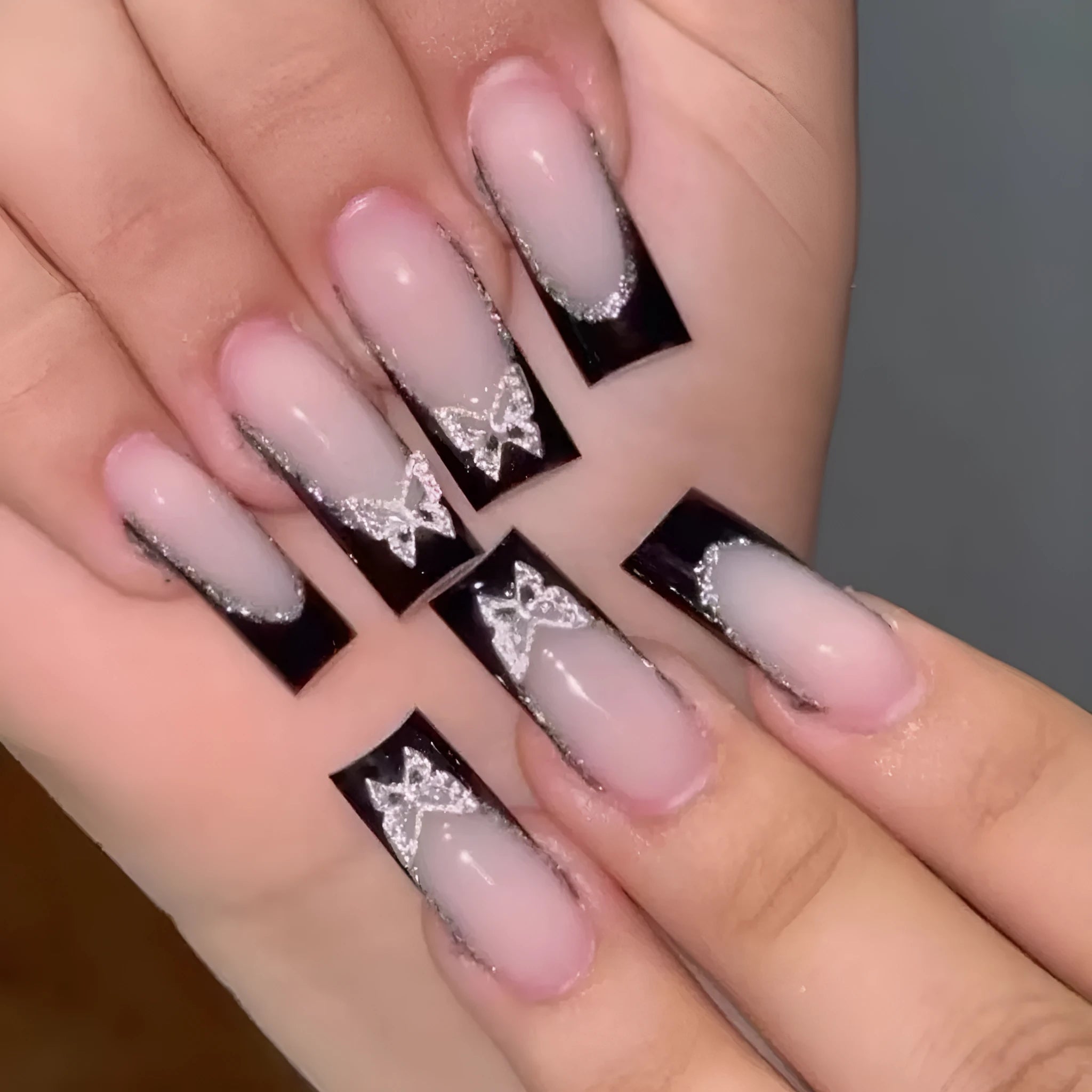 Black French style false nails with butterfly pattern and glittering finish, medium length
