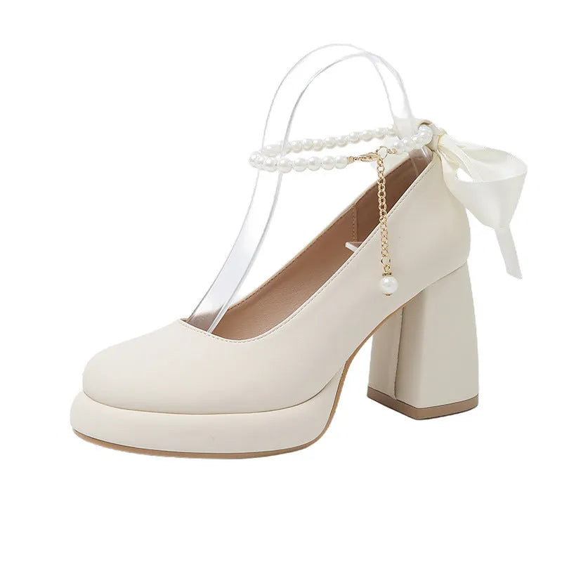 Women's beige Mary Jane shoes with chunky low heel, pearl decoration, and ankle strap buckle on a round toe.