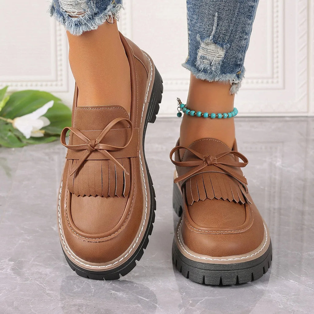 Black plus size women's loafers with tassel and bow knot decoration on a chunky low heel.