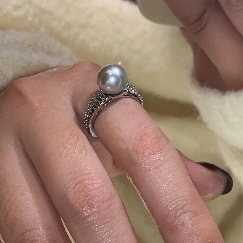 Copper geometric open ring with black pearl on a model's finger, showing adjustable gap.