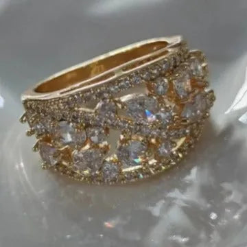 Women's round hollow fashion ring with gemstone accents on a copper band, shown in gold and platinum finishes.