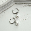 A pair of women's geometric pearl hoop earrings with alloy construction and titanium steel posts.