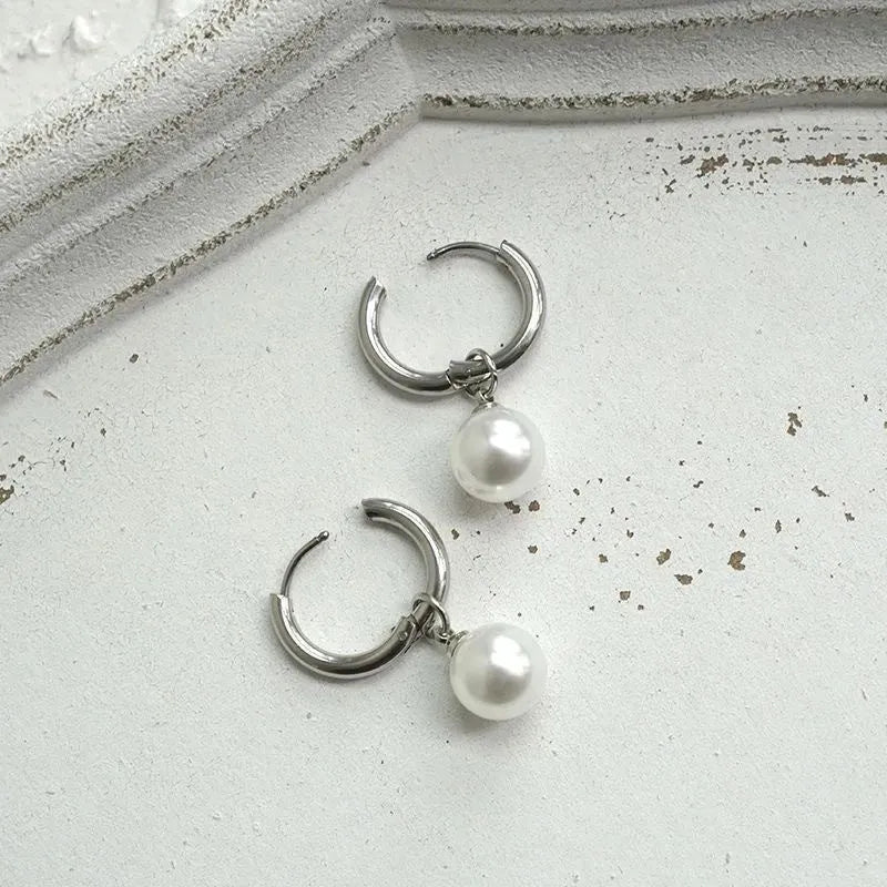 A pair of women's geometric pearl hoop earrings with alloy construction and titanium steel posts.