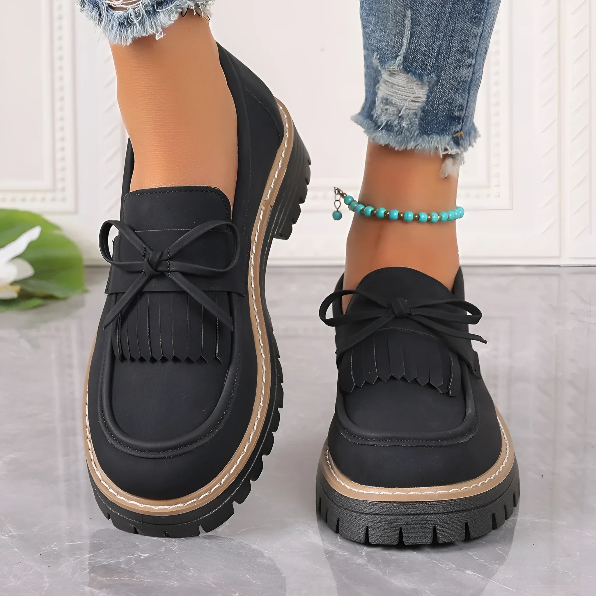 Black plus size women's loafers with tassel and bow knot decoration on a chunky low heel.