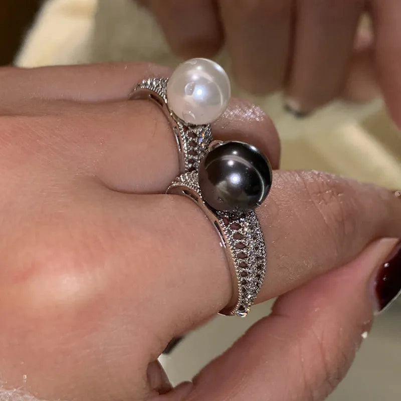 Copper geometric open ring with black pearl on a model's finger, showing adjustable gap.